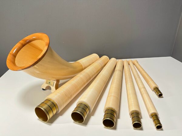 Set von Alphörnern mit hochwertigen Holzmundstücken auf weißem Tisch präsentiert. Perfekt für authentischen Alpenklang.