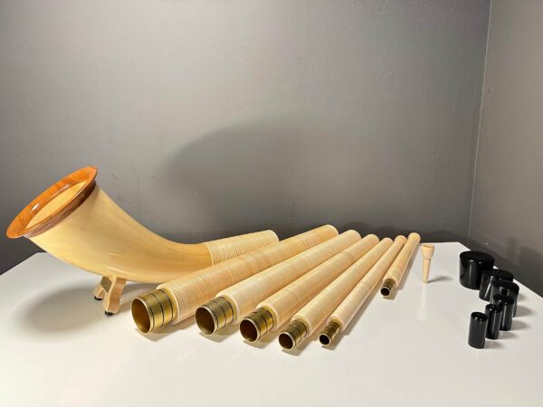 Handgefertigtes Alphorn mit hochwertigem Holzmundstück, präsentiert auf einem Tisch, unterstreicht natürliche Musikalität.