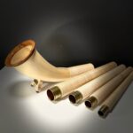 Edles Alphorn aus Holz mit abnehmbaren Mundstücken vor dunklem Hintergrund, präsentiert von NATURINSTRUMENTE Heimatklang.