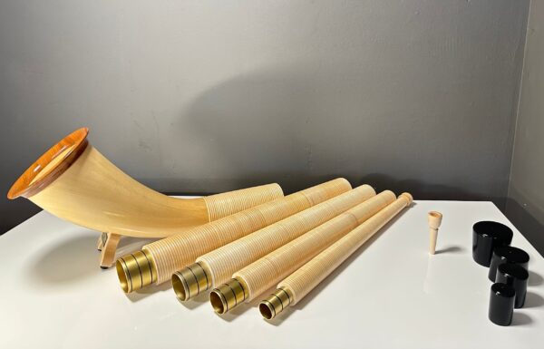 Alpenhorn mit hochwertigen Holzmundstücken auf einem Tisch, präsentiert von NATURINSTRUMENTE Heimatklang.