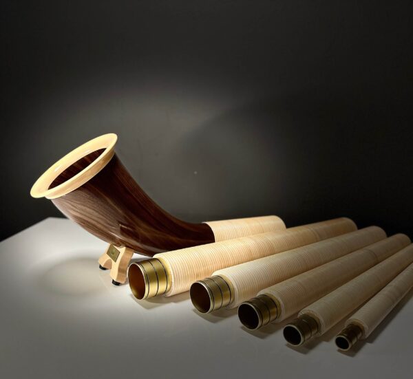 Alphorn mit edlem Holzmundstück und segmentierten Röhren vor dunklem Hintergrund, präsentiert von NATURINSTRUMENTE Heimatklang.