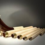 Alphorn aus edlem Holz mit mehreren Segmenten und Mundstück, präsentiert auf glänzendem Tisch bei NATURINSTRUMENTE Heimatklang.