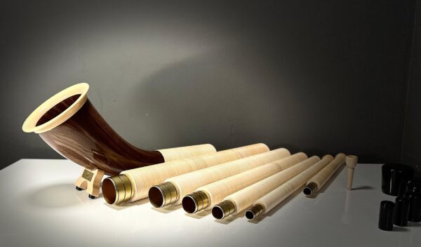 Alphorn aus edlem Holz mit mehreren Segmenten und Mundstück, präsentiert auf glänzendem Tisch bei NATURINSTRUMENTE Heimatklang.