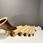 Hochwertige Alphörner mit Holzmundstücken und Einzelteilen, präsentiert auf einem Tisch bei NATURINSTRUMENTE Heimatklang.