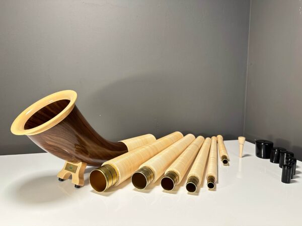 Hochwertige Alphörner mit Holzmundstücken und Einzelteilen, präsentiert auf einem Tisch bei NATURINSTRUMENTE Heimatklang.