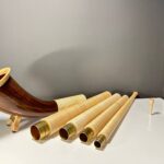 Alphorn mit abnehmbaren Holzmundstücken und Segmenten, präsentiert auf einem Tisch. Perfekte Wahl für Naturinstrumente.