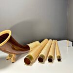 Hochwertiges Alphorn mit mehreren Holzsegmenten und Holzmundstück auf einem weißen Tisch, präsentiert die Naturinstrumente Heimatklang.