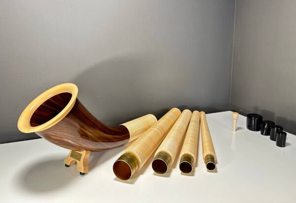 Hochwertiges Alphorn mit mehreren Holzsegmenten und Holzmundstück auf einem weißen Tisch, präsentiert die Naturinstrumente Heimatklang.