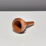 Hochwertiges Holzmundstück für Alphorn, präsentiert auf einem glänzenden Untergrund. Ideal für natürliche Klangerlebnisse.