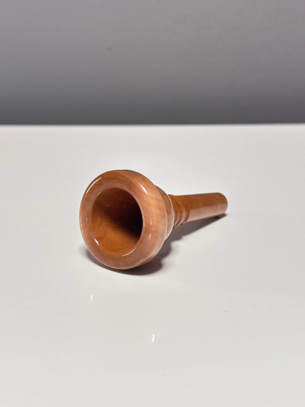 Hochwertiges Holzmundstück für Alphorn, präsentiert auf einem glänzenden Untergrund. Ideal für natürliche Klangerlebnisse.