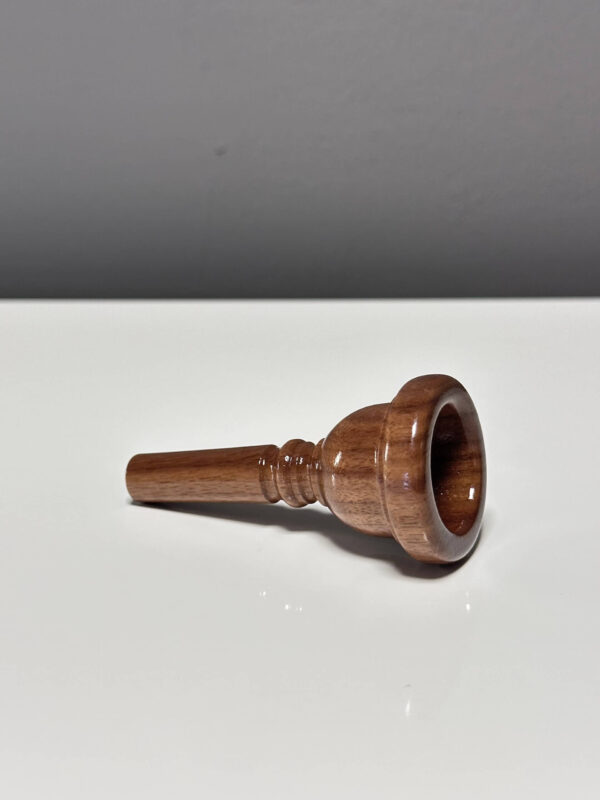 Handgefertigtes Holzmundstück für Alphorn, präsentiert auf einer glatten Fläche, ideal für NATURINSTRUMENTE-Enthusiasten.