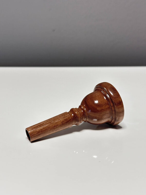 Handgefertigtes Holzmundstück für Alphörner, elegant poliert, liegt auf weißem Untergrund.