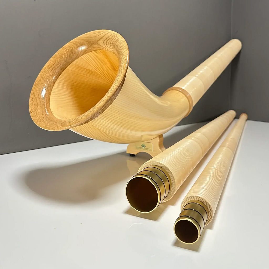 Alphorn aus hellem Holz mit Mundstücken auf weißem Hintergrund, im Kontext des NATURINSTRUMENTE Heimatklang.
