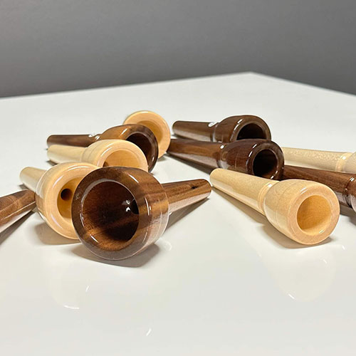 Hochwertige Holzmundstücke für Alphörner, kunstvoll arrangiert, spiegeln handwerkliche Exzellenz wider.