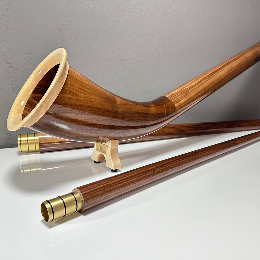 Edles Alpenhorn aus glänzendem Holz mit detaillierten Mundstücken, präsentiert von NATURINSTRUMENTE Heimatklang.
