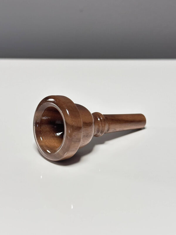 Handgefertigtes, glänzendes Holzmundstück für Alphörner, präsentiert auf einem weißen Hintergrund von NATURINSTRUMENTE Heimatklang.