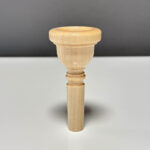 Hochwertiges Holzmundstück für Alphorn auf grauem Hintergrund, perfekt für authentische Klangerlebnisse mit Naturinstrumenten.