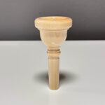 Hochwertiges Holzmundstück für Alphorn auf weißem Tisch, handgefertigt für besten Klang bei NATURINSTRUMENTE Heimatklang.