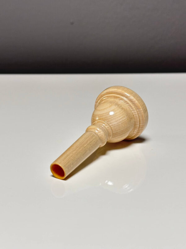 Hochwertiges Holzmundstück für Alphorn auf reflektierendem Untergrund, ideal für den perfekten Heimatklang.