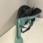 Grüne Tragetasche für Alphorn, geöffnet auf weißem Tisch, ideal für den sicheren Transport von Naturinstrumenten.