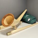 Alphorn und Holzmundstück von NATURINSTRUMENTE, präsentiert mit grünem Tragebeutel, ideal für Heimatklang-Enthusiasten.