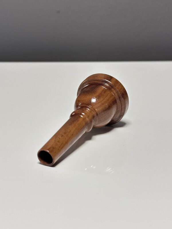 Handgefertigtes Holzmundstück für Alphörner, präsentiert auf einer weißen Fläche, spiegelt traditionelle Handwerkskunst wider.