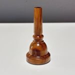 Hochwertiges Holzmundstück für Alphörner, glänzend und detailliert gearbeitet, auf einem Tisch präsentiert.