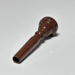 Fein gearbeitetes Holzmundstück für Alphörner, präsentiert auf einer weißen Oberfläche, symbolisiert naturnahen Klang.