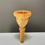 Hochwertiges Holzmundstück für Alphorn vor grauer Wand, Teil des NATURINSTRUMENTE Heimatklang Angebots.
