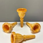 Vier hochwertige Holzmundstücke für Alphörner auf weißer Oberfläche, ideal für erstklassigen Klang bei Heimatklang Naturinstrumenten.