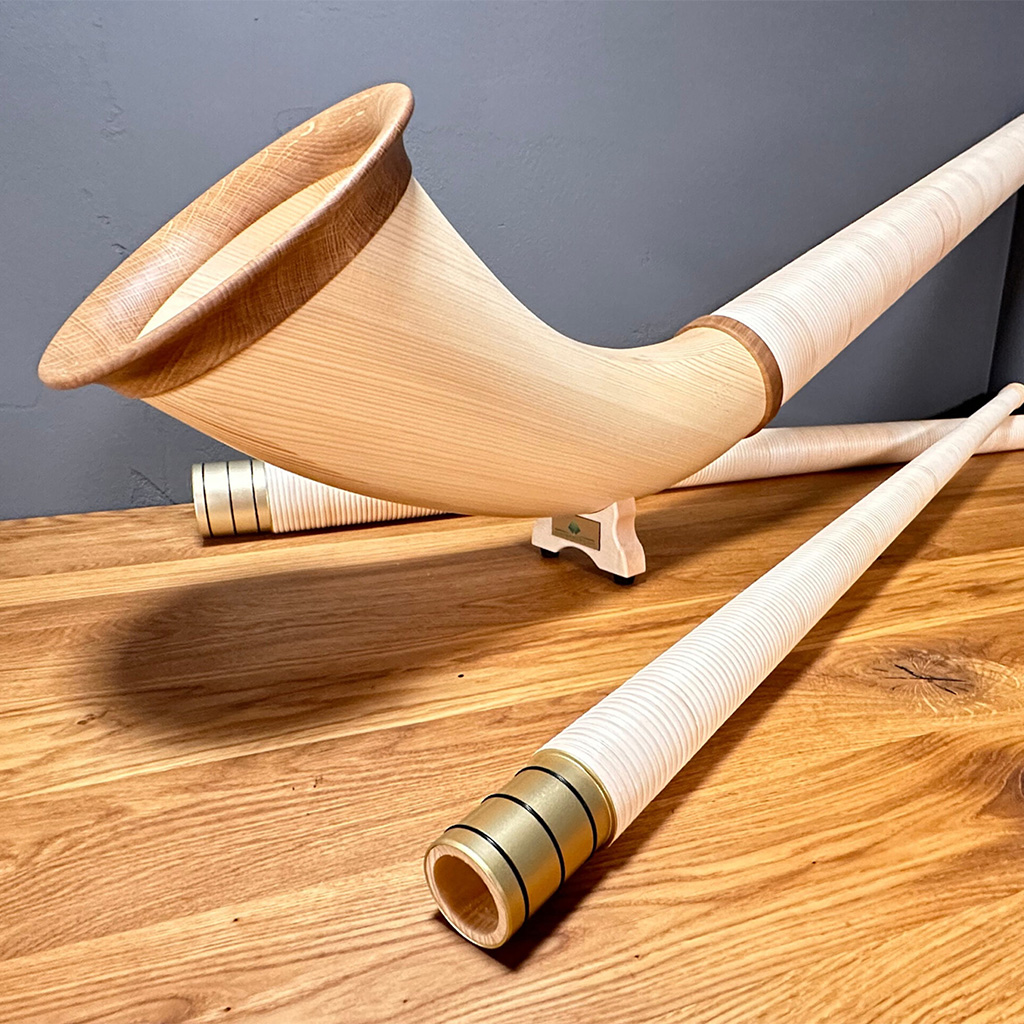 Alphorn auf Holzoberfläche, detailreich gestaltet mit hochwertigen Holzmundstücken für den perfekten Heimatklang-Sound.