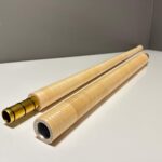 Zwei hochwertige Holzteile eines Alphorns mit goldener Verbindungsstelle, präsentiert auf einer weißen Fläche.