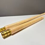 Zwei hochwertige Alphorn-Mundstücke aus Holz mit goldenen Verbindungsstücken auf weißem Hintergrund, elegant präsentiert.