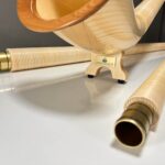 Alpenhorn aus hellem Holz mit hochwertigen Metallverbindungen, präsentiert auf einer sauberen, modernen Oberfläche.