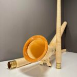 Alphorn und Holzmundstück auf einem Tisch, hochwertige Naturinstrumente von Heimatklang. Perfekt für traditionelle Musik.