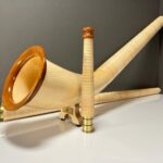 Alphorn aus hellem Holz mit veredeltem Mundstück auf weißem Tisch, präsentiert von NATURINSTRUMENTE Heimatklang.