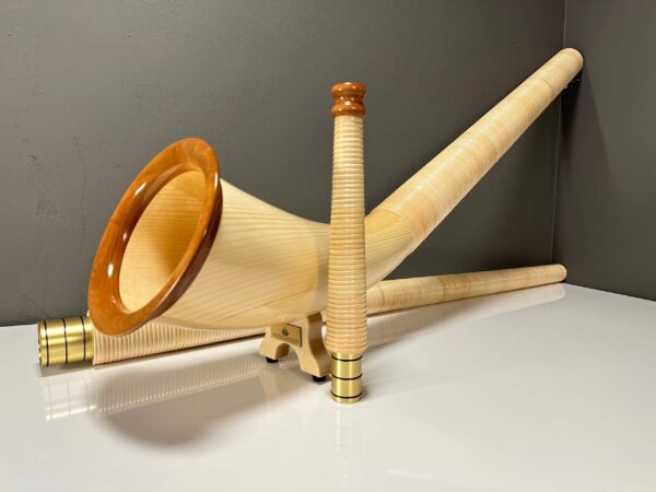 Alphorn aus hellem Holz mit veredeltem Mundstück auf weißem Tisch, präsentiert von NATURINSTRUMENTE Heimatklang.