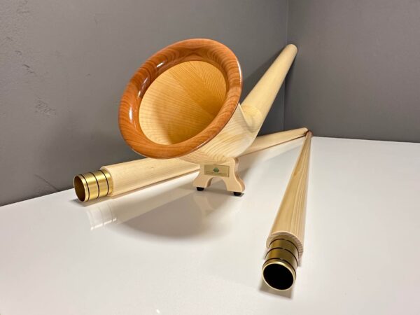 Hochwertiges Alphorn mit Holzmundstück auf weißem Tisch, präsentiert von NATURINSTRUMENTE Heimatklang.
