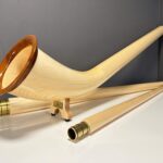 Hochwertiges Alphorn mit edlen Holzmundstücken, gezeigt in stilvollem Ambiente, betont die Handwerkskunst von Heimatklang.