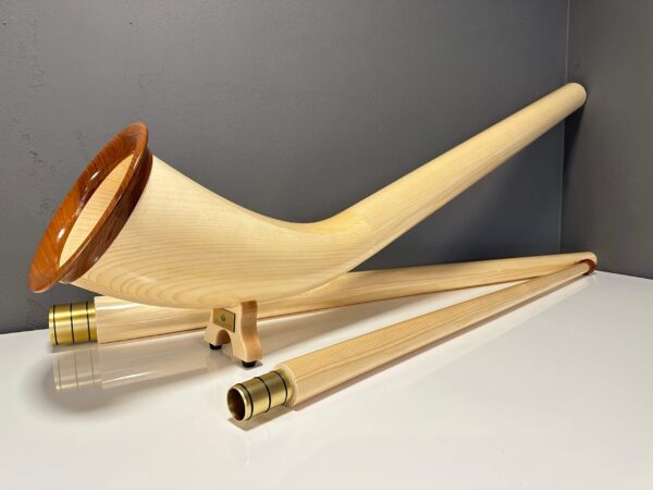 Alphorn mit hochwertigen Holzmundstücken auf weißem Tisch, ideal für NATURINSTRUMENTE Heimatklang, zeigt Handwerkskunst.