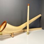 Alpenhorn aus hellem Holz mit elegantem Design, präsentiert auf einem Tisch; Teil der NATURINSTRUMENTE Heimatklang Kollektion.