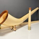 Hochwertige Alphörner mit edlen Holzmundstücken auf einem Tisch, präsentiert von NATURINSTRUMENTE Heimatklang.