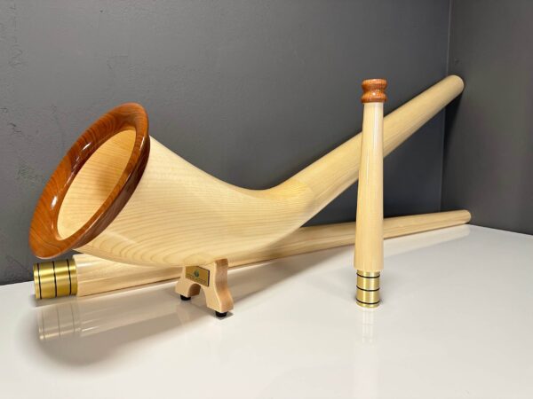 Hochwertige Alphörner mit edlen Holzmundstücken auf einem Tisch, präsentiert von NATURINSTRUMENTE Heimatklang.