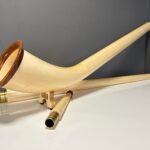 Alphorn mit hochwertigen Holzmundstücken auf weißem Tisch, präsentiert von NATURINSTRUMENTE Heimatklang.
