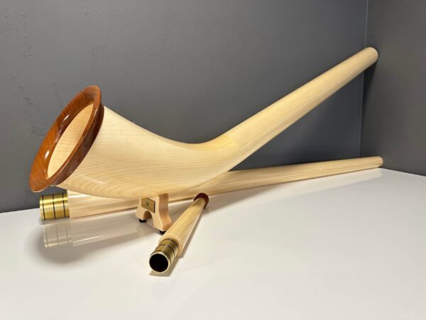 Alphorn mit hochwertigen Holzmundstücken auf weißem Tisch, präsentiert von NATURINSTRUMENTE Heimatklang.