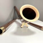 Elegantes Alphorn aus Holz mit feinem Finish, präsentiert auf weißem Hintergrund; ideal für Heimatklang-Enthusiasten.