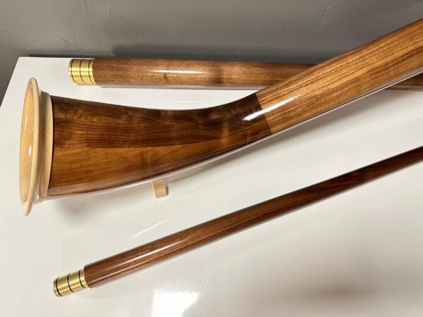 Glänzende Alphörner aus edlem Holz auf weißem Hintergrund, gefertigt von Heimatklang für Klangqualität und Tradition.