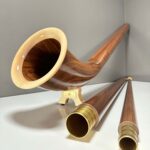 Alphorn und edle Holzmundstücke in Nahaufnahme auf weißem Untergrund, präsentiert von NATURINSTRUMENTE Heimatklang.