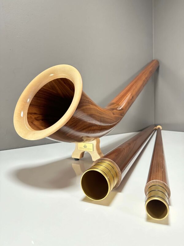 Alphorn und edle Holzmundstücke in Nahaufnahme auf weißem Untergrund, präsentiert von NATURINSTRUMENTE Heimatklang.