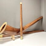Elegantes Alphorn mit edlen Holzmundstücken in einem schlichten Raum, präsentiert von NATURINSTRUMENTE Heimatklang.
